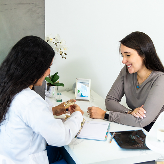 Dentist and patient sitting at desk and looking at model of teeth