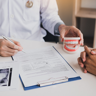 Dentist pointing to form on clipboard and holding a denture