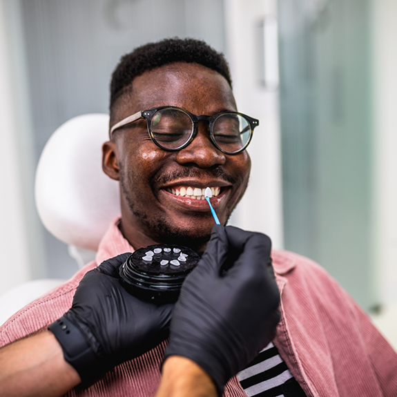 Man with glasses having teeth shade matched for cosmetic dentistry in Reynoldsburg