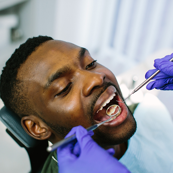 Man leaning back in chair having teeth examined