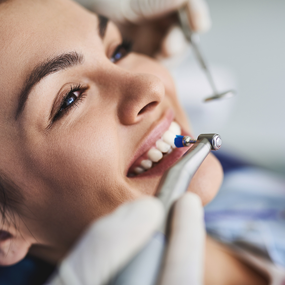 Woman having teeth cleaned with electric brush