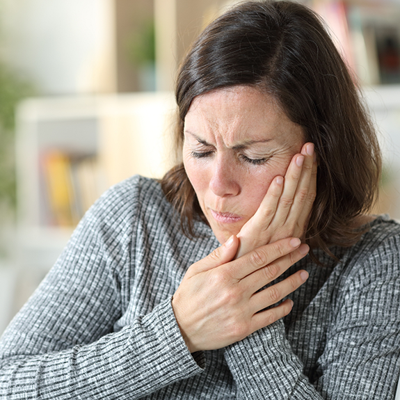 Woman in grey sweater with jaw pain