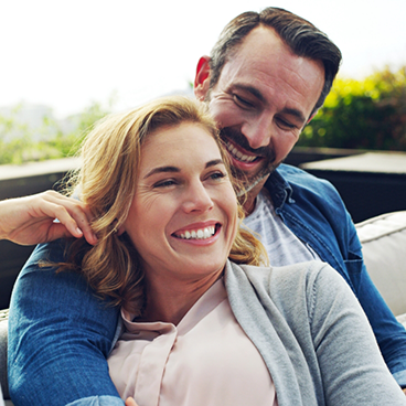 Man hugging woman from behind outside smiling