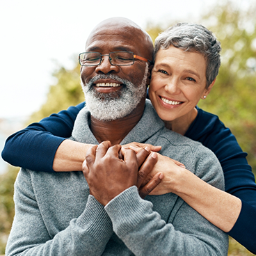 Woman hugging man from behind while smiling