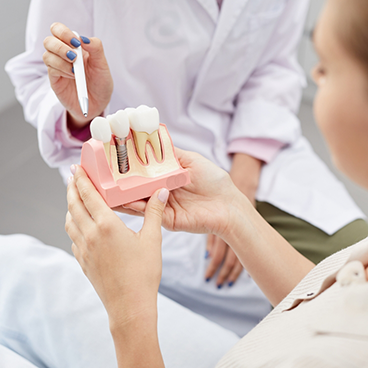 Dental patient looking at a dental implant model