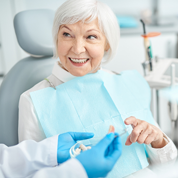 Senior woman in dental chair talking to dentist