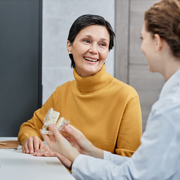 Senior woman talking to dental team member and smiling