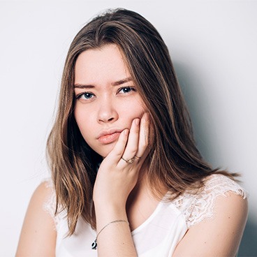 Woman rubbing her cheek looking concerned