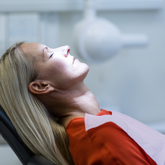 Woman in red shirt relaxed in dental chair