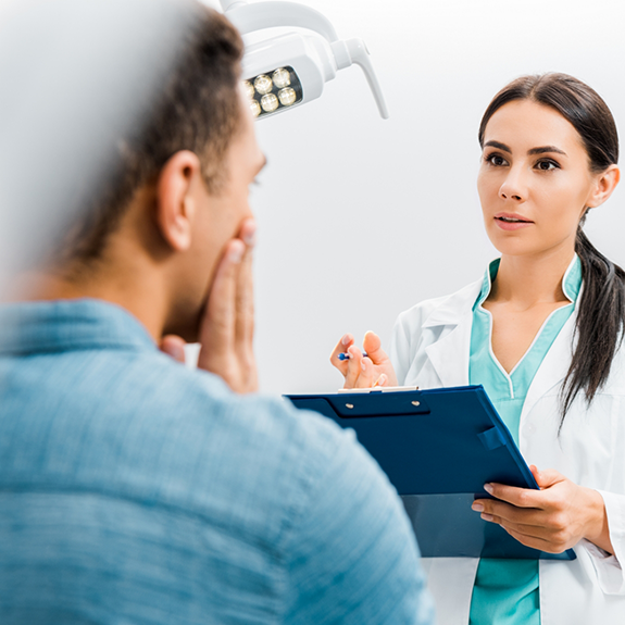 Dentist holding tablet talking to patient