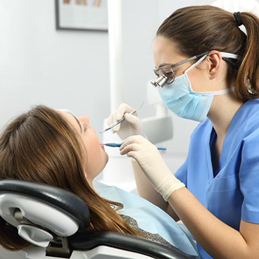 Dentist with mask treating a patient