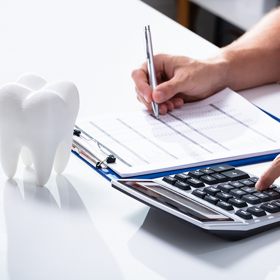 Filling out form with tooth and calculator on desk