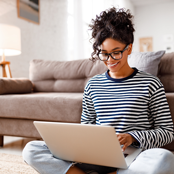 Smiling woman in striped shirt working on laptop