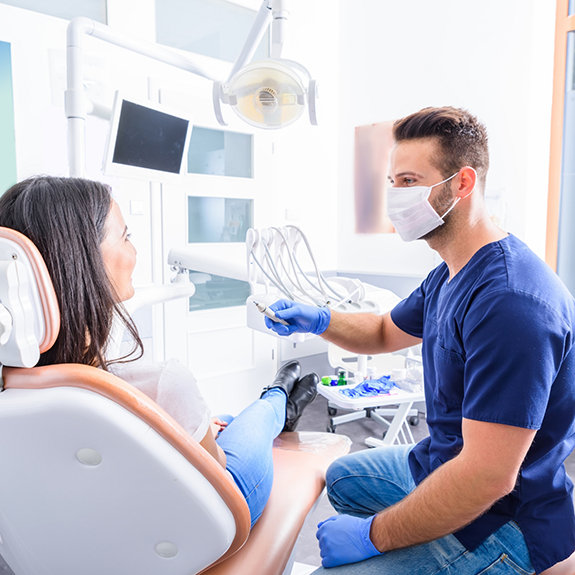 Dentist with mask speaking to female patient