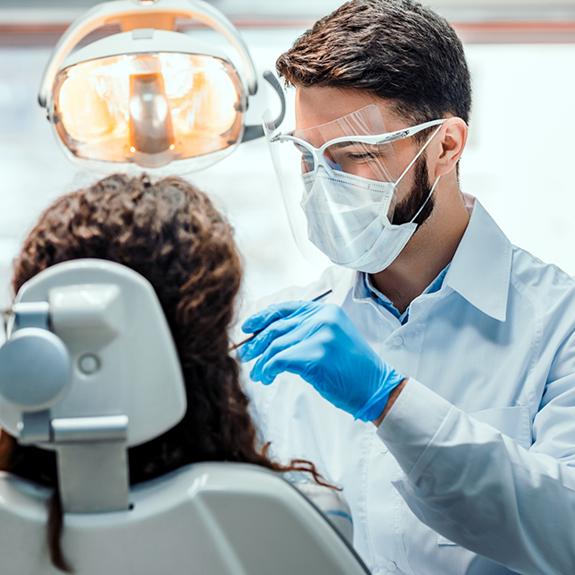 Dentist with protective masks treating patient