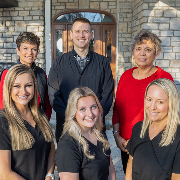 Dental team standing outside of building and smiling