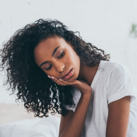 Woman in white shirt rubbing jaw in pain