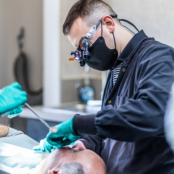 Dentist with mask talking to senior woman in dental chair