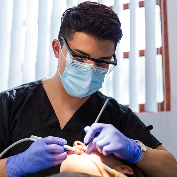 Dentist with mask treating patient