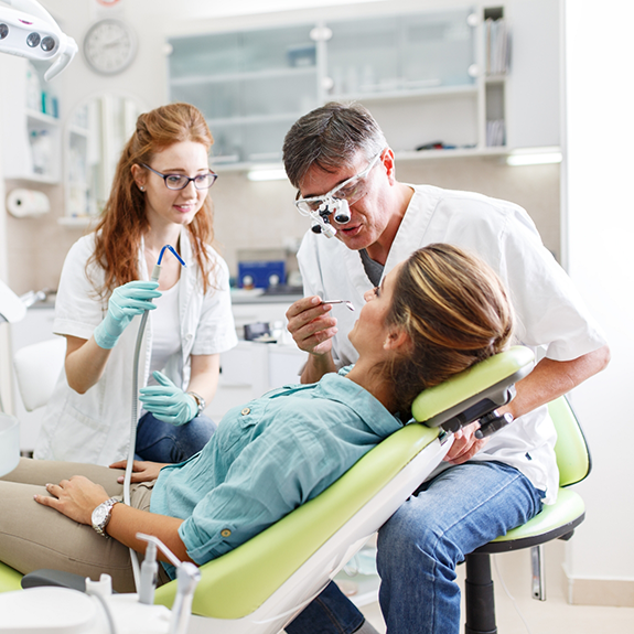 Female patient being treated by dentist and hygienist