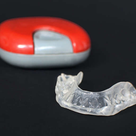 Athletic mouthguard on black surface next to case