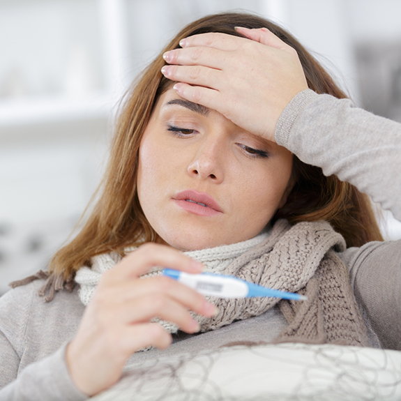 Woman with fever looking at thermometer