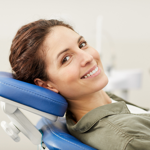 Woman leaning back in dental chair and smiling