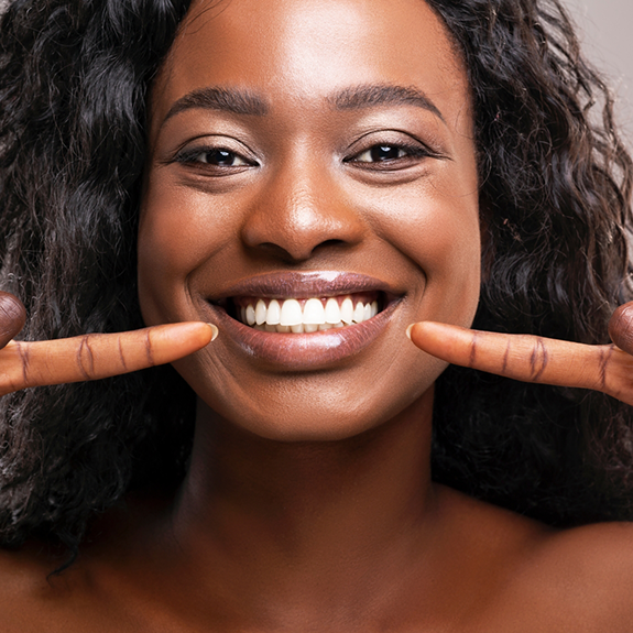 Close up of woman pointing to her smile