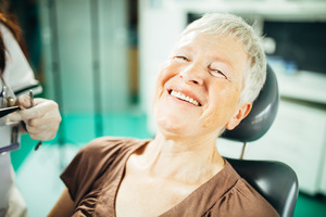 Woman leaning back in dental chair and smiling